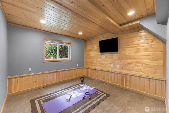 A pine-paneled home gym or flex space with TV hookup and cork flooring offers the ideal environment for yoga, workouts, or a playroom.