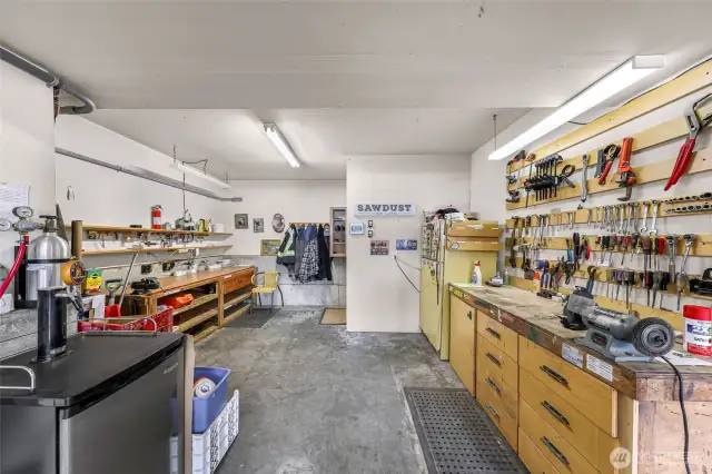 The well-equipped workshop is a dream for hobbyists or professionals alike, offering wall-to-wall storage, pegboard tool organization, and ample work surface