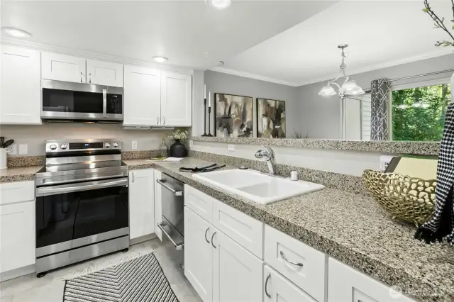 Modern Kitchen with premium appliances - featuring neutral countertops, white cabinetry, and a sleek DCS two-drawer dishwasher for flexible and efficient cleanup. The stove/oven and microwave were installed new in 2021.