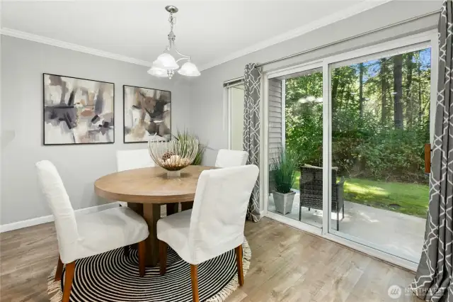 Dining Area with scenic views - bright and inviting space with sliding glass doors that open to a private patio and lush greenbelt backdrop.