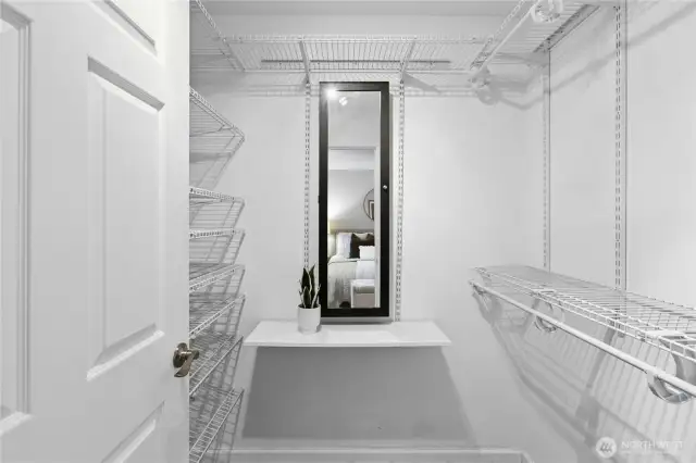 Spacious walk-in closet featuring built-in shelving for organized storage, a mirror, and a custom jewelry cabinet - combining style and functionality in one luxurious space.