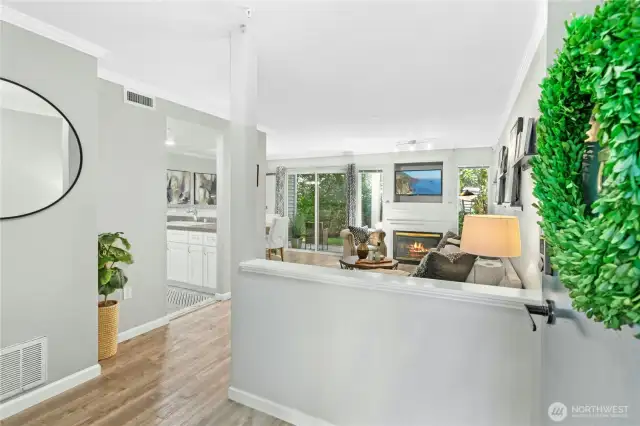 Step inside to an open, light-filled living space with stylish flooring, a cozy gas fireplace, and seamless flow into the kitchen and dining areas.