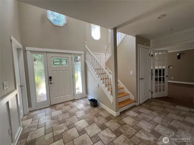 Bright foyer featuring decorative glass door, natural light, and open staircase