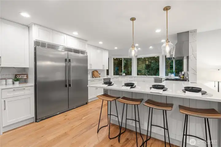 Kitchen features an XL stainless steel fridge, Miele gas range and hood, quartz counterops with a seating are