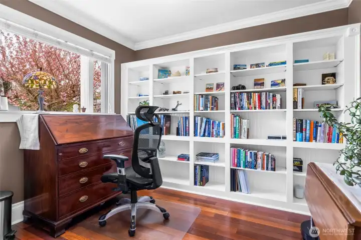 Front office w/ custom built-in bookshelves, overlooking the street.