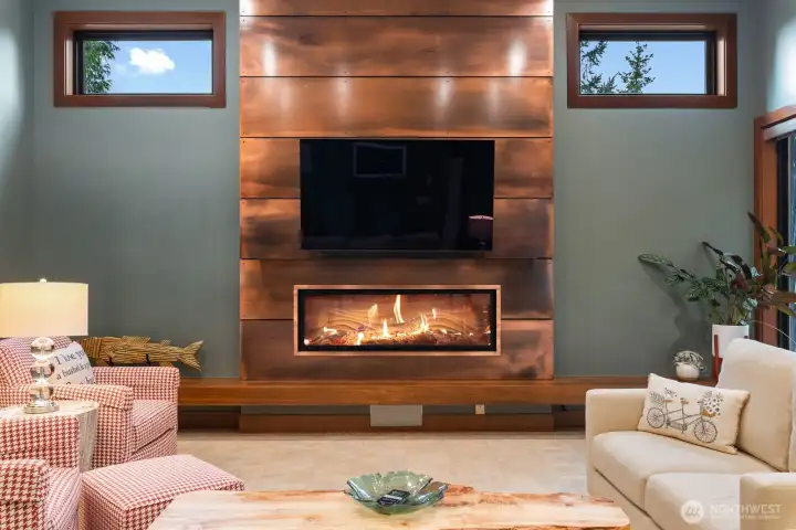 Linear fireplace with bronze accent wall, built in benches and well thought out high windows make this an inviting space to cuddle up with a good book or movie.