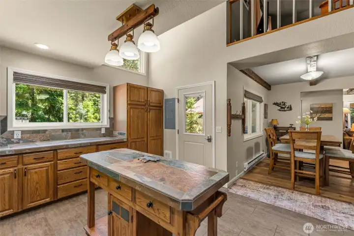 Welcoming guests with warm mountain character, the kitchen features rich wood cabinetry, tile countertops, a functional center island, and abundant natural light. Welcoming guests with warm mountain character, the kitchen features rich wood cabinetry, tile countertops, a functional center island, and abundant natural light.
