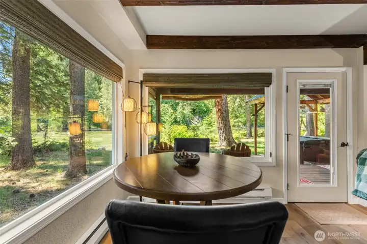 Window-lined dining nook with beautiful river views, exposed beam accents, and direct access to the covered deck—an inviting space to enjoy meals surrounded by nature. Window-lined dining nook with beautiful river views, exposed beam accents, and direct access to the covered deck—an inviting space to enjoy meals surrounded by nature.