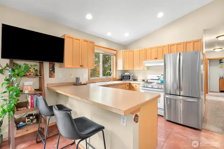 Bright and functional kitchen with vaulted ceilings, generous counter space, bar seating, and an open layout that connects seamlessly to the dining and living areas. Bright and functional kitchen with vaulted ceilings, generous counter space, bar seating, and an open layout that connects seamlessly to the dining and living areas.