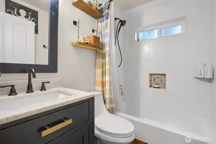 Full Bath – Updated full bath showcases a modern vanity with stone countertop, stylish fixtures, and a beautifully tiled tub and shower surround with decorative accent niche. Full Bath – Updated full bath showcases a modern vanity with stone countertop, stylish fixtures, and a beautifully tiled tub and shower surround with decorative accent niche.