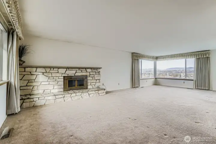 Over sized living room with fireplace and view of the mountains and valley.  Hardwoods under carpet.