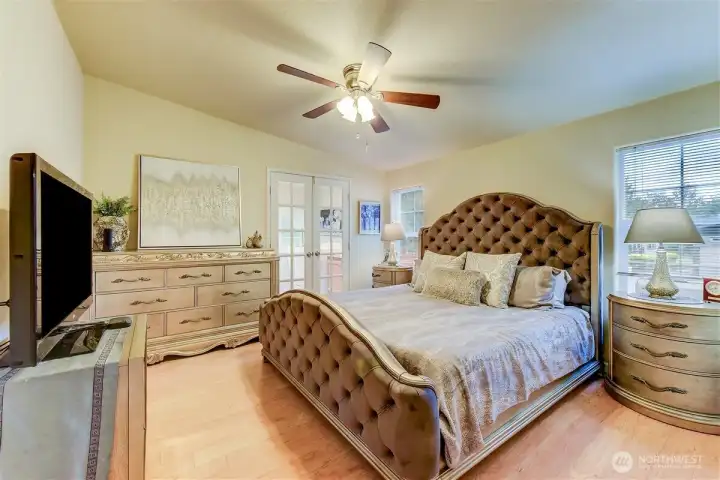 Natural light abounds in the primary bedroom with en-suite beyond the glass French doors. Natural light abounds in the primary bedroom with en-suite beyond the glass French doors.