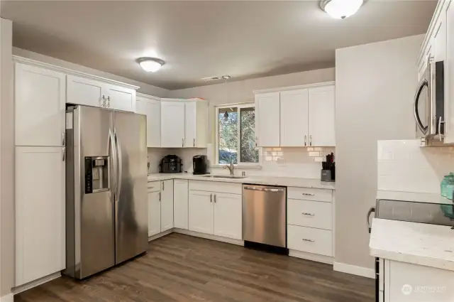 Granite counters with subway tile backsplash from counter to bottom of cabinets and stainless appliances.