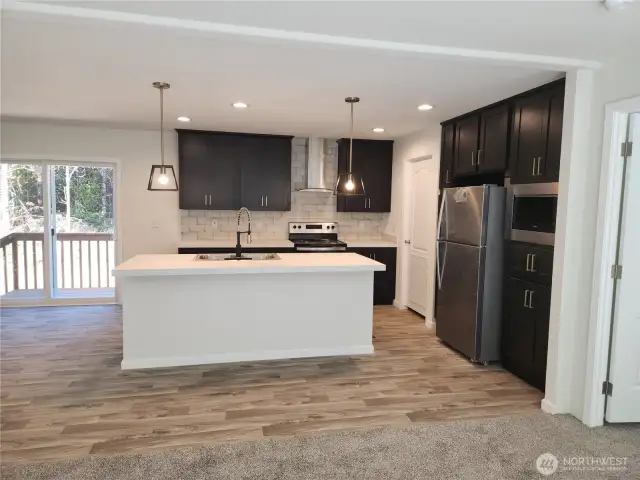 Wonderful contemporary style kitchen with sleek black cabinetry, stainless steel appliances and copper tone hardware on the cabinets.