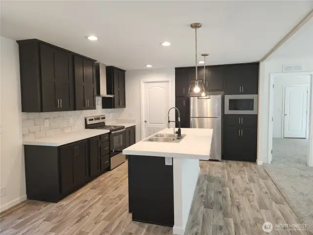 This eat-in kitchen offers plenty of space off the island to seat more guests.  The dishwasher is in the island by the sink for more convenience.  The door off the kitchen is the utility room.