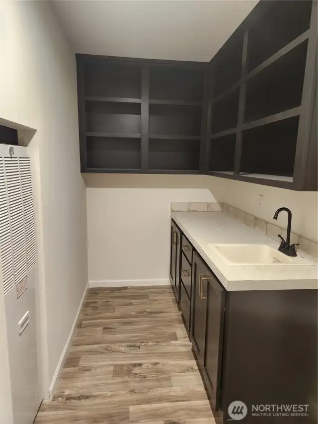 This utility room has matching cabinetry as the kitchen with lots of storage room, as well as a utility sink.  Furnace to the left of the photo.