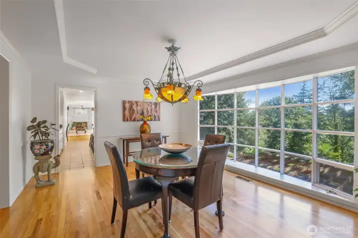The formal dining room is framed by a large picture window overlooking the wooded backdrop. Detailed millwork and a tray ceiling elevate the room, making it an ideal setting for hosting dinners and celebrations.