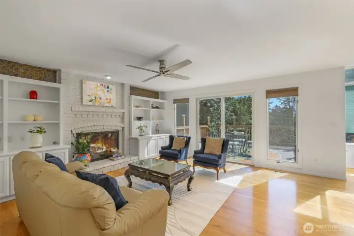 The family room centers around a stately fireplace framed by built-in shelving, expansive windows and sliding doors to the deck, this inviting space blends comfort and functionality.