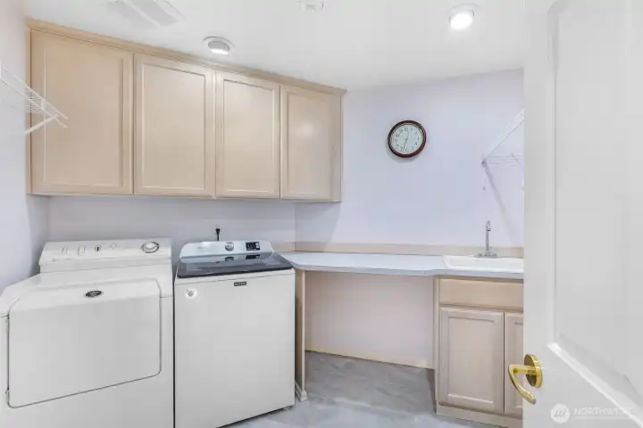 The laundry room is designed with efficiency in mind, offering plenty of cabinetry, counter space, and a utility sink. Thoughtful organization makes everyday tasks more manageable.