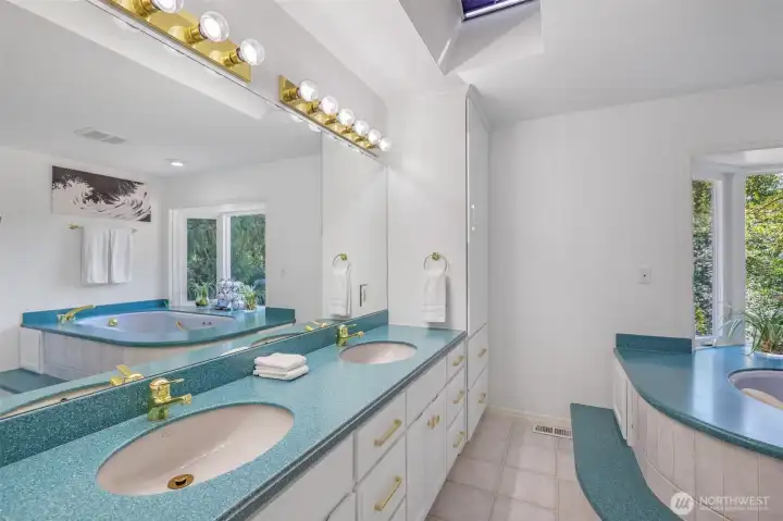 The primary bath offers a spa-inspired layout with dual sinks, abundant counter space, and bright natural light from overhead skylights. Its thoughtful design provides both function and comfort for daily living.