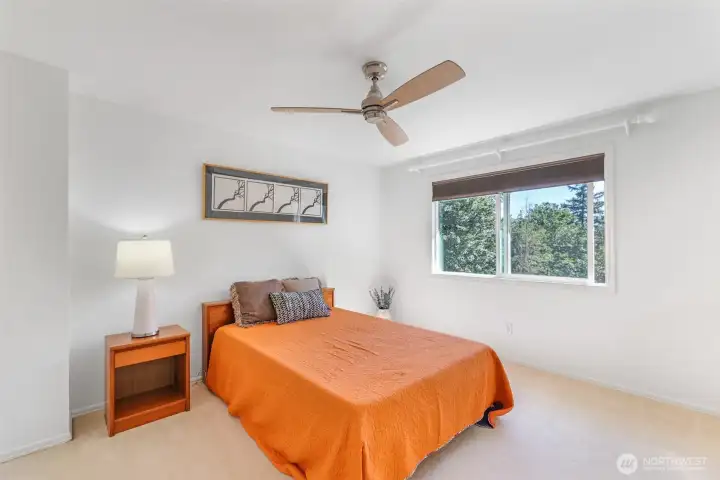 Another secondary bedroom provides flexibility for family, guests, or additional workspace, with expansive windows framing treetop views.