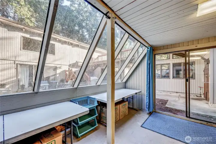 Glass house has a sliding glass door and large slanted windows.