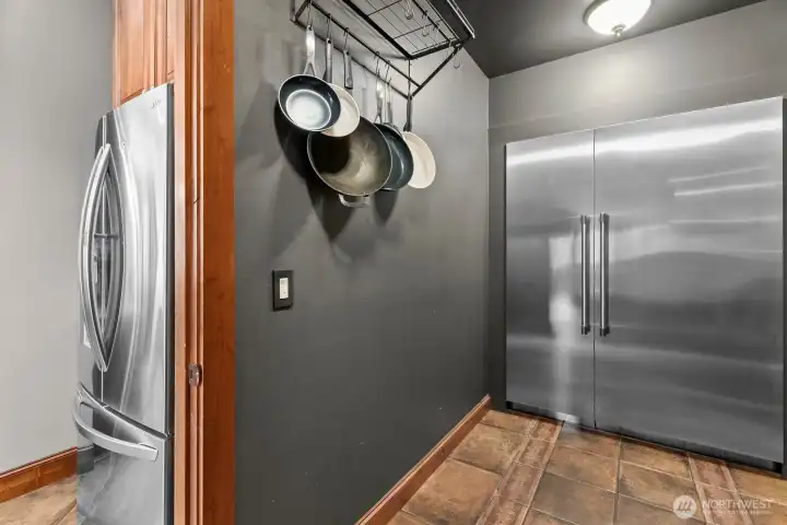 Large walk-in pantry has a built in Thermador fridge and freezer for extra storage.