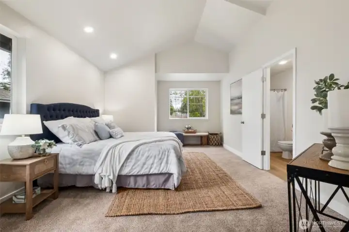 The spacious primary suite is filled with natural light and offers a peaceful retreat at the end of the day. Its generous layout provides several options and extra room to unwind. Soaring vaulted ceilings elevate the suite, adding volume, brightness, and a sense of luxury to the space.