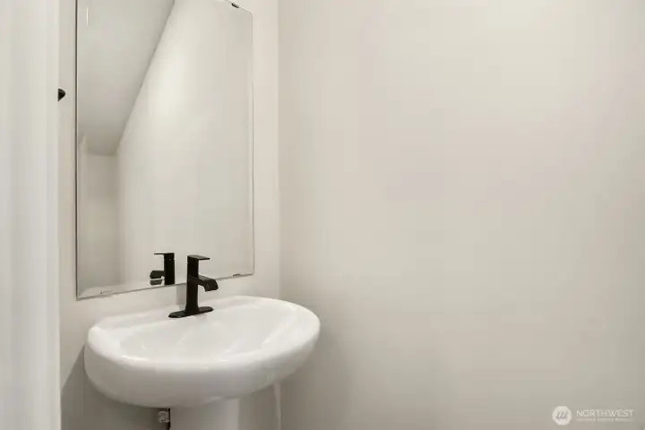 Main floor powder room with pedestal sink and matte black finishes