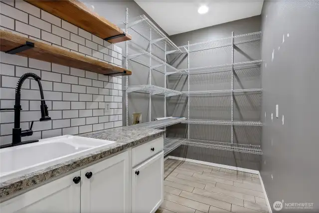 enormous walk in pantry accompanied by a farmhouse sink