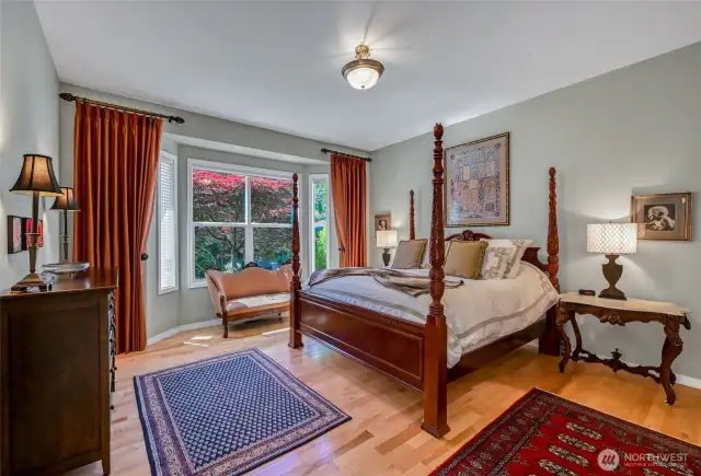 The spacious primary suite has hardwood floors, two walk-in closets and overlooks the backyard gardens.