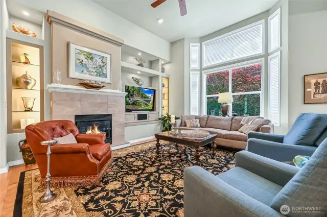 Banks of glass, lighted shelves flank the fireplace with its new surround and custom media built-in.