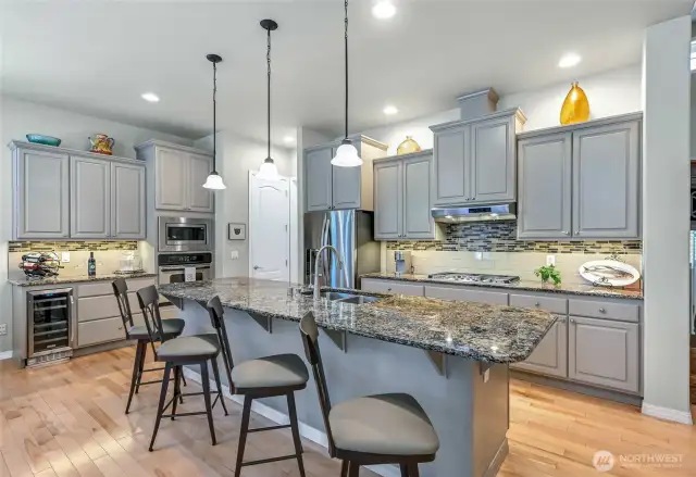 The spectacular kitchen with custom painted cabinets, slab granite counters, full height tile backsplash, under cabinet lights, pendant lights, full sized pantry, wine fridge & newer convection microwave and gas cooktop.