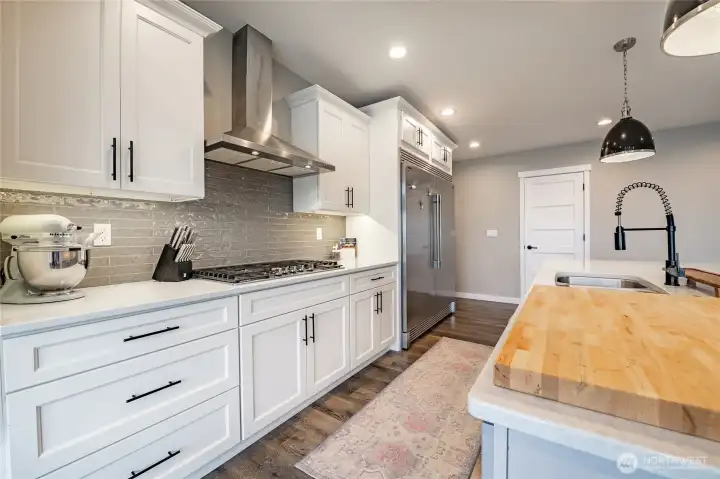 Gas cooktop with hood, tile backsplash, abundant counter and cabinet space, under-cabinet lighting and more