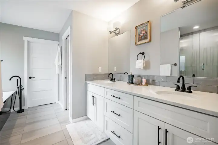 Primary bath with undercounter sinks, oil rubbed bronze fixtures, Tile backsplash, dual mirrors, soaking tub and glass / tile shower
