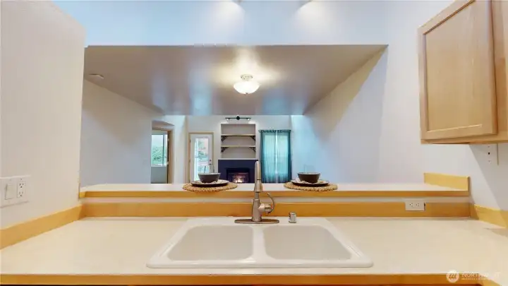 Looking into the living room and dining room.  The Gas log fireplace adds so much warmth and ambiance to the home!  The raised breakfast bar allows for a break between the formal and informal.  You are never separated from your guests and your prep areas are not visible from the dining or livingroom areas.