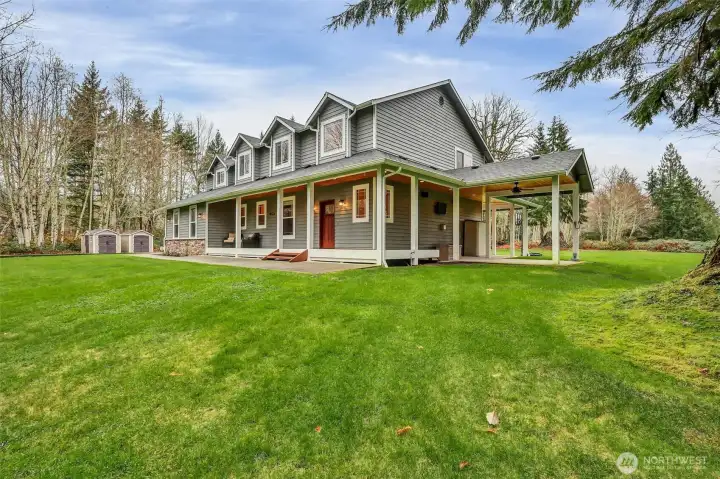 Expansive front lawn and serene natural backdrop.