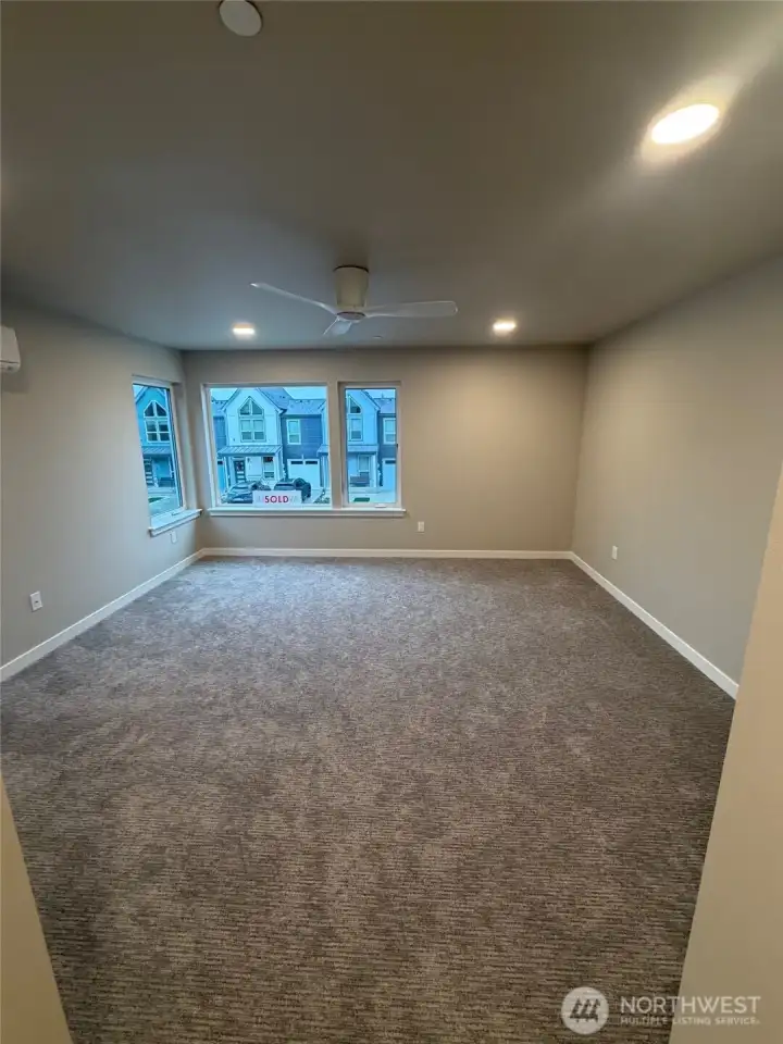Primary bedroom with ceiling fan & flooded with natural sunlight