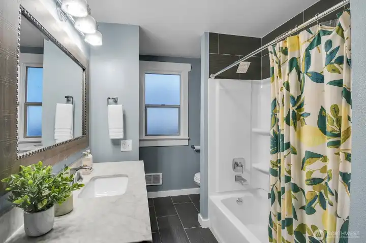 Features tile floors, a tiled tub surround, and a marble-topped vanity for a polished look.