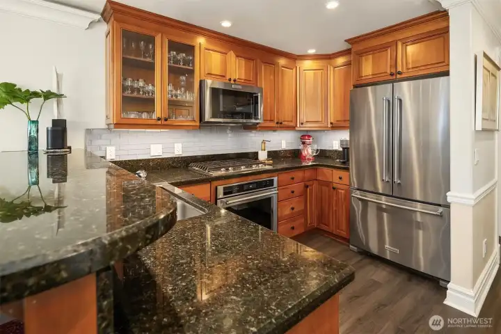 Chef’s kitchen with granite counters, stainless steel appliances, under cabinet lighting, and gas cooking.