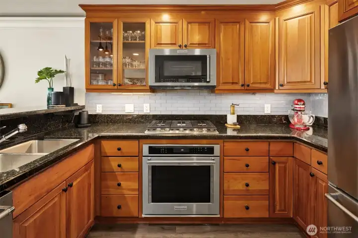 Chef’s kitchen with granite counters, stainless steel appliances, under cabinet lighting, and gas cooking.