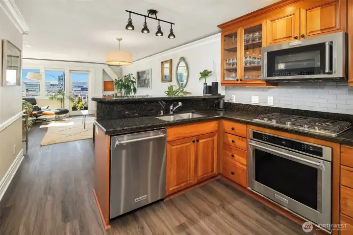 Chef’s kitchen with granite counters, stainless steel appliances, under cabinet lighting, and gas cooking.