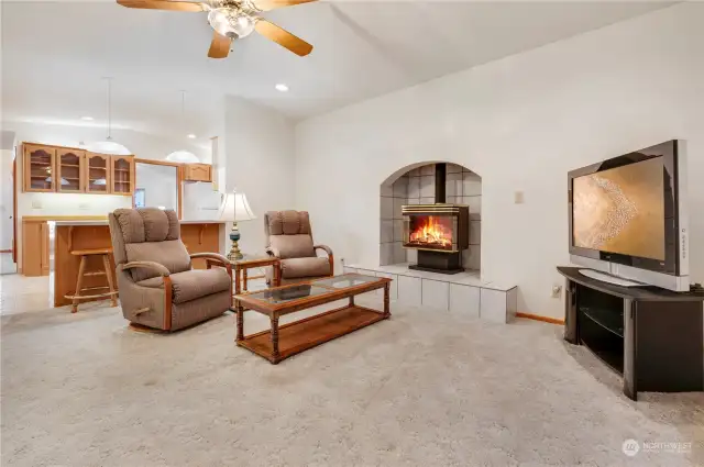 Eating bar in kitchen, gas stove and ceiling fan in vaulted family room