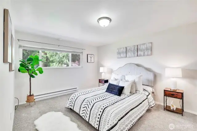 Spacious primary bedroom also allows you to look out at soothing green foliage.