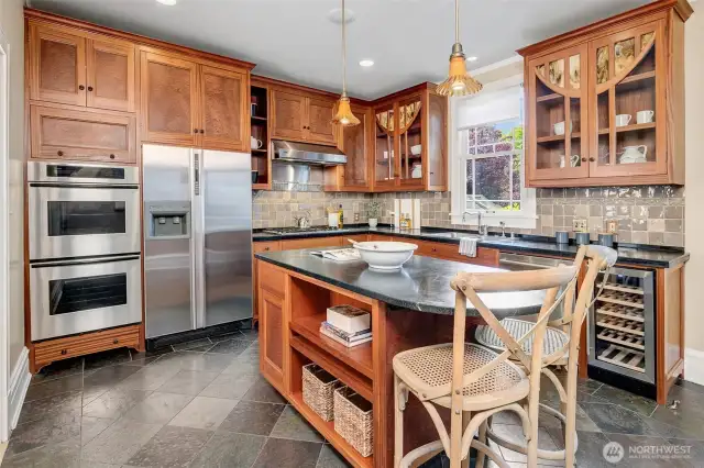 The reimagined Chef’s kitchen with a generous island provides both prep space and seating for two. Custom mahogany cabinetry, crafted by a renowned local furniture maker, echoes the home's arched doors and features restoration glass panes.