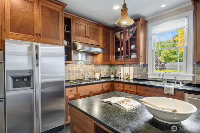 Exquisite custom cabinetry, handcrafted from rich mahogany by a renowned local artisan, showcases intricate craftsmanship and restoration glass panes that reflect the home's signature arched doors.