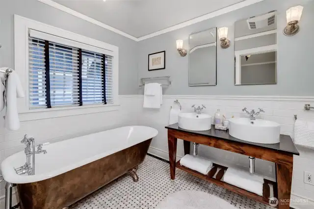 Upstairs, the beautifully restored marble-tiled bathroom retains its original charm with a refinished clawfoot tub, restored inside and out, alongside a separate shower and a stylish double vanity.