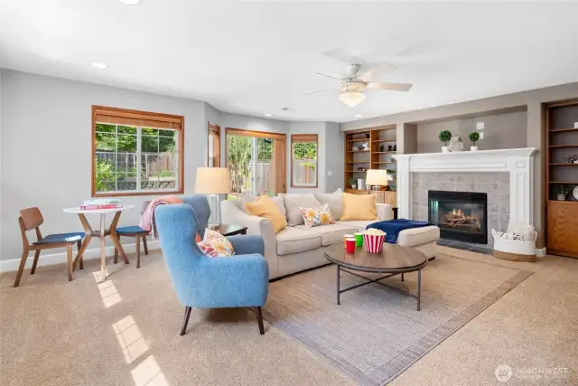 Coming from the office, we head down the very wide hallway into the fun room. This oversized Family Room will be amazing in whatever capacity you use it. Home gym, game room, or simple family gathering space? This room features ceiling fan and beautiful gas fireplace, flanking bookshelves and storage cabinets. Notice the beautiful bayed windows and slider leading out to the lower yard and the East side of the home.