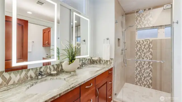 Luxurious spa-like bath with special tilework with accents, oversized shower with dual shower heads and two hand helds, and illuminated mirrors with defrosters.  There is also a separate toilet closet with custom organizers.
