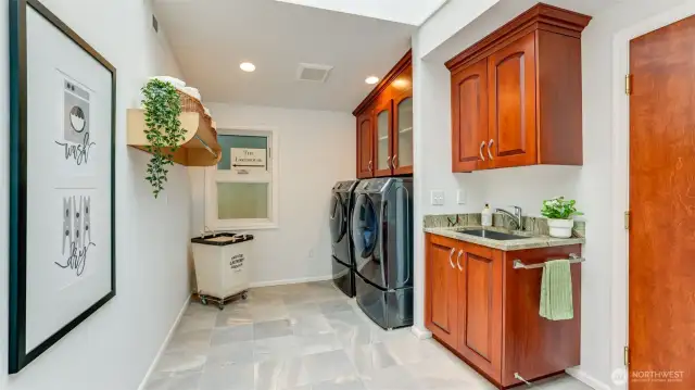 Spacious laundry room with tile flooring, cabinets, a deep sink and washer and dryer remain. This room connects the main 2 car garage to the rest of the home.
